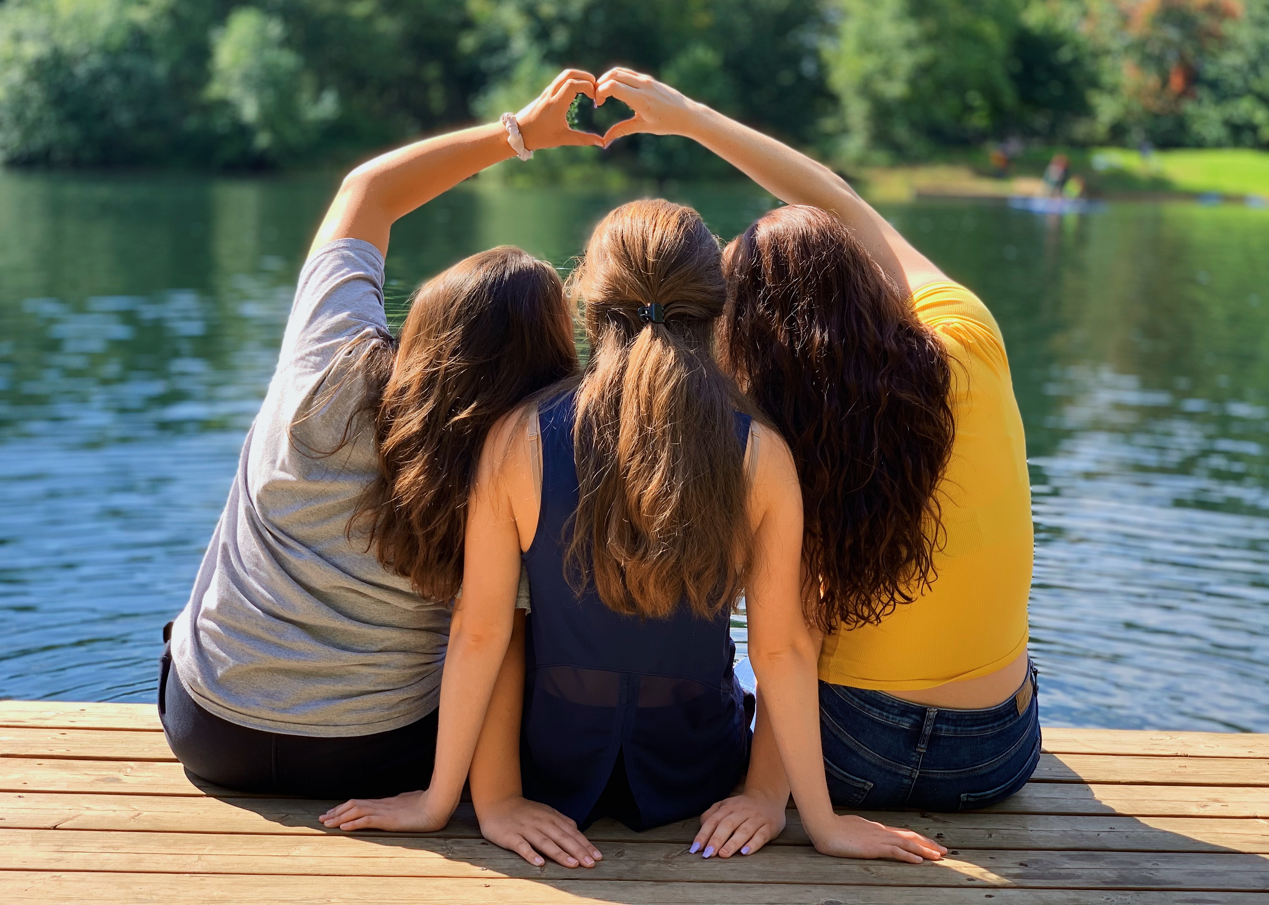 3 girls hugging and making a heart with their hands